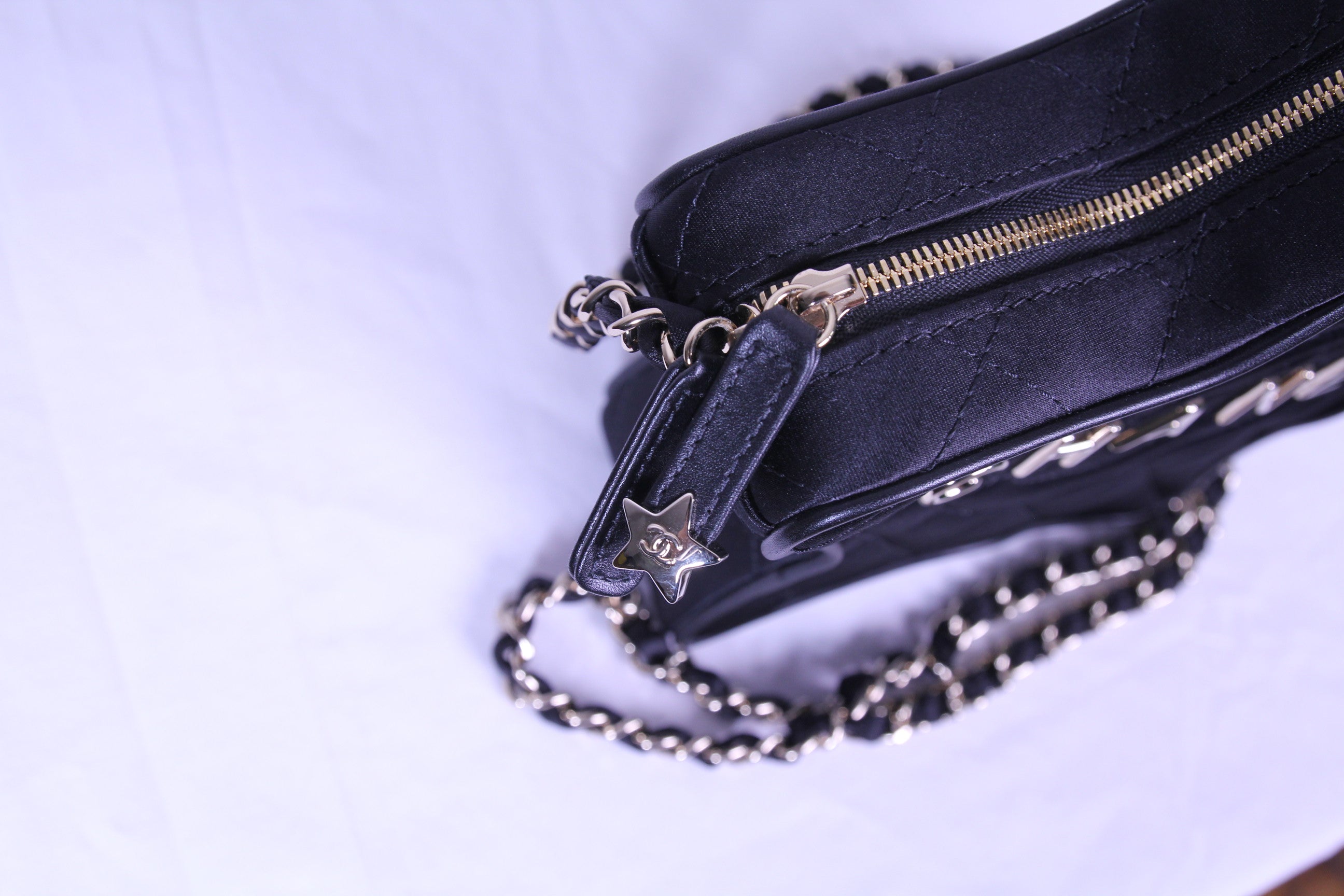 Zipper of Chanel star handbag in finished in black satin